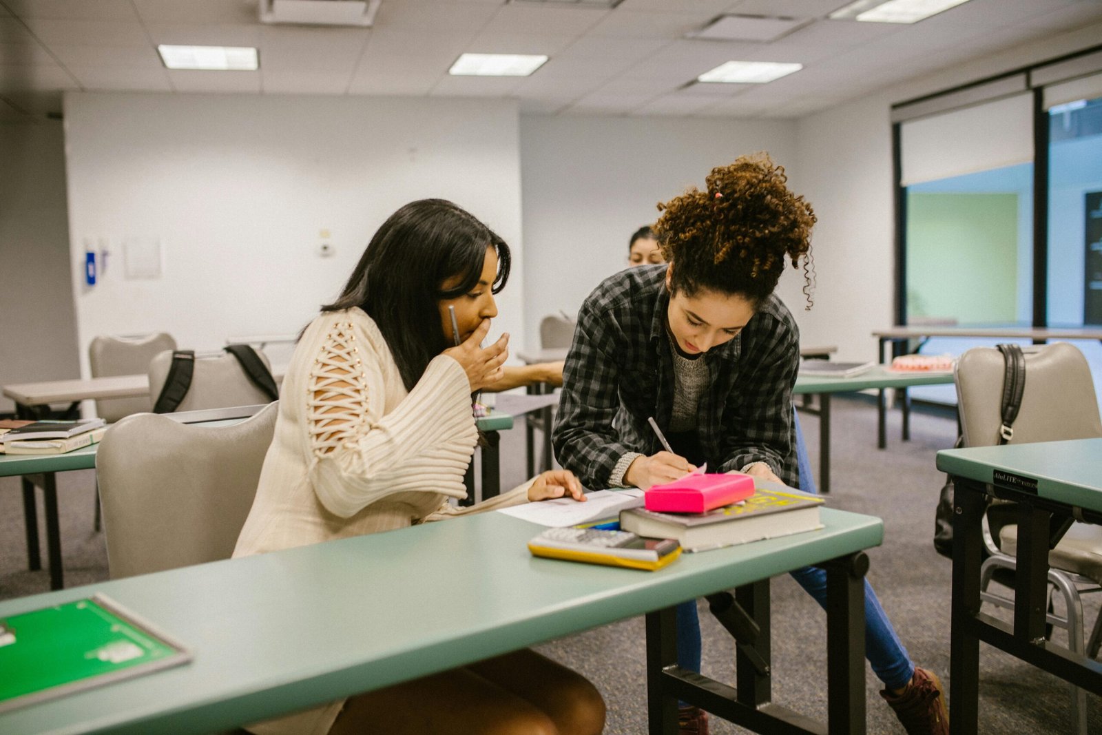 Two female students collaborate in a classroom setting, focusing on their studies.